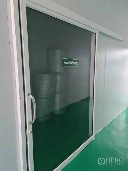 工厂 出售在Bang Pa-in, Phra Nakhon Si Ayutthaya - 推拉玻璃门通往原料仓，内有成卷材料。