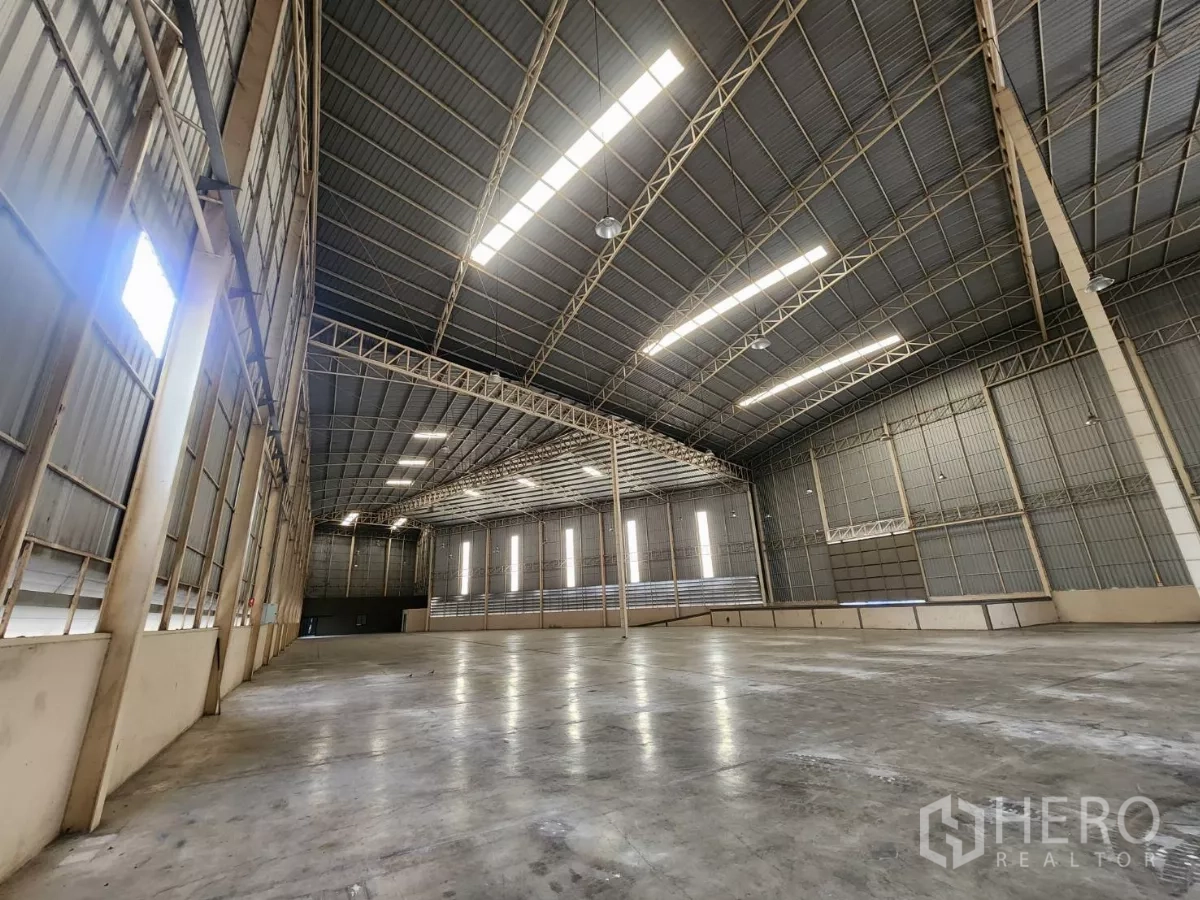 Warehouse for rent in Mueang Samut Sakhon, Samut Sakhon - Spacious warehouse interior featuring a high clear-span steel roof, skylights, and durable polished concrete floor.