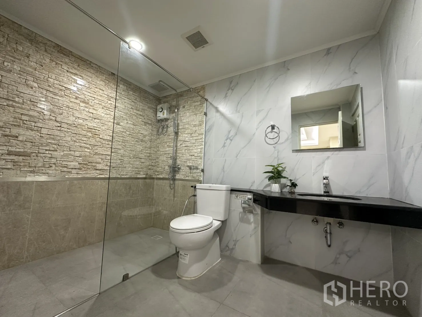 Condominium for rent in Watthana, Bangkok - Second bathroom with walk-in glass shower and stone accent wall.