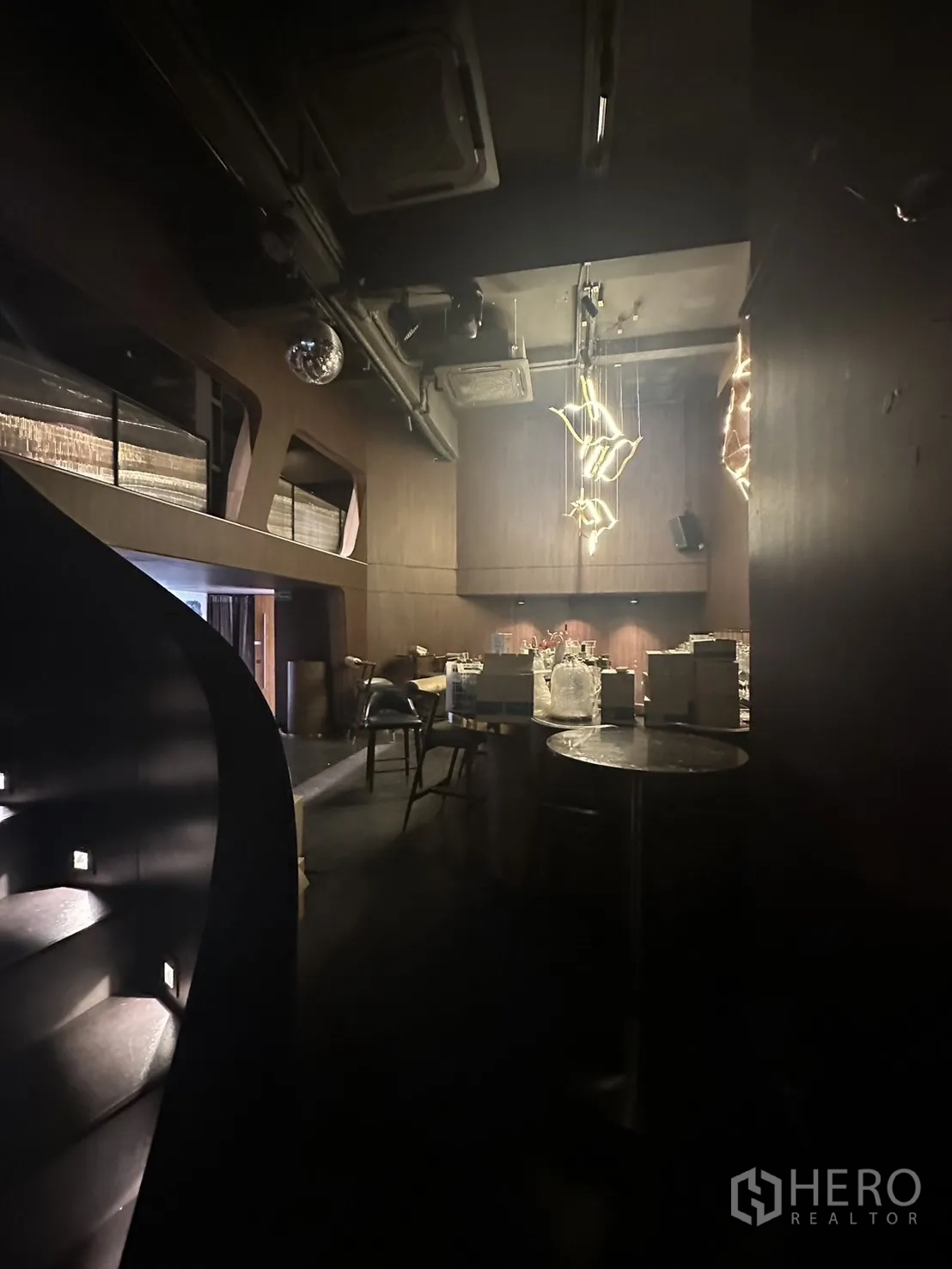 店屋 出租在Watthana, Bangkok - 楼梯视角的挑高吧区，木质墙面与艺术吊灯