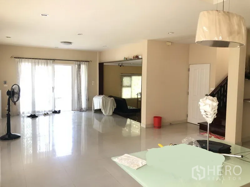 独立式住宅 出租或出售在Bang Kapi, Bangkok - 采光充足的开放式客厅，亮面地砖与窗帘，旁有楼梯。