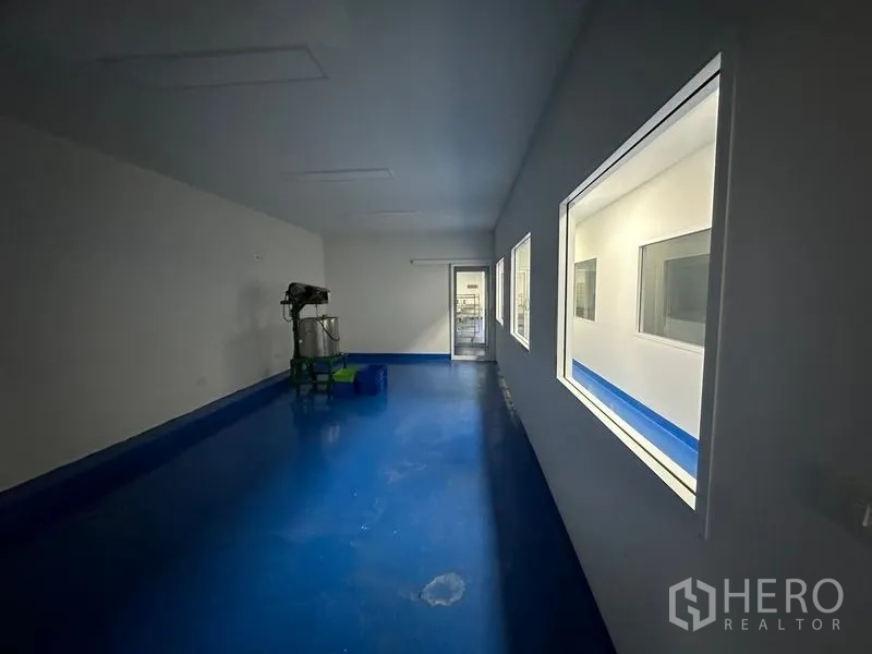 Warehouse for rent in Pak Kret, Nonthaburi - Production room with an industrial mixer, blue epoxy floor and viewing windows.