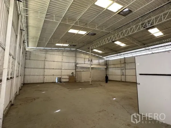 Warehouse for rent in Min Buri, Bangkok - High-ceiling warehouse interior with steel trusses, skylights, and an open clear-span floor.