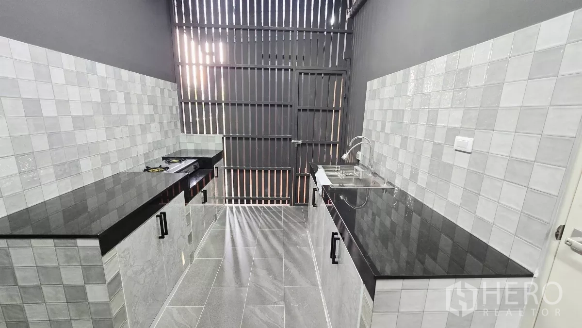 Detached House for rent in Prawet, Bangkok - Separate Thai kitchen with tiled walls, black countertops and a gas hob.