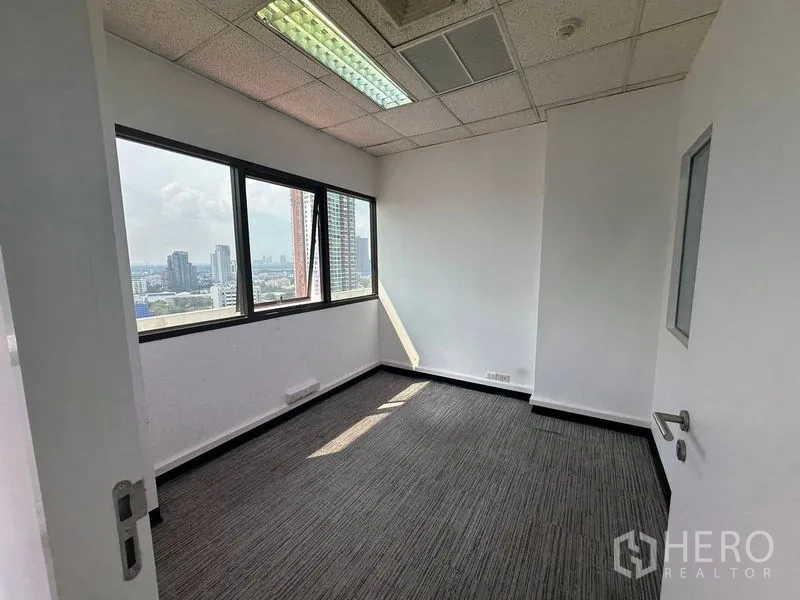办公空间 出租在Watthana, Bangkok - 带大窗与城市景观的私密办公室，上方网格吊顶。