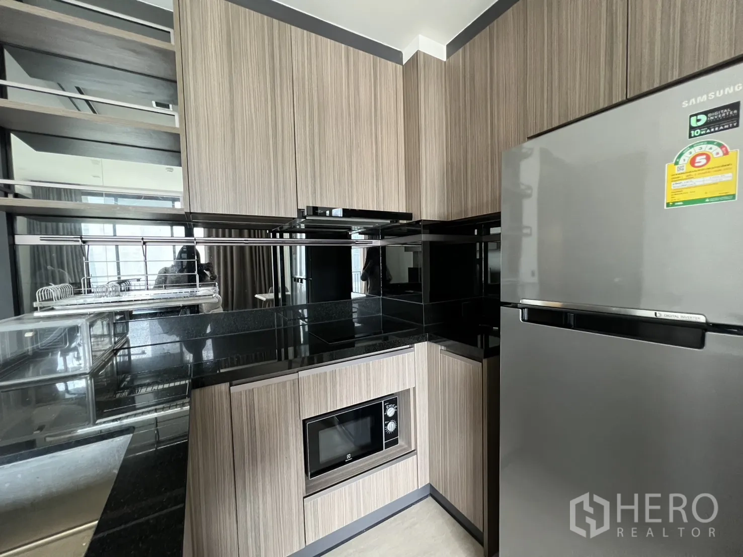 公寓 for rent in Watthana, Bangkok - 厨房一角配不锈钢冰箱、木质柜与镜面挡板。