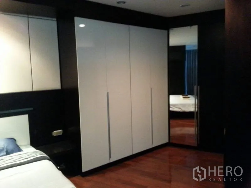 公寓 出租或出售在Pathum Wan, Bangkok - 卧室一角呈现白色衣柜、深色木饰与亮泽地板。