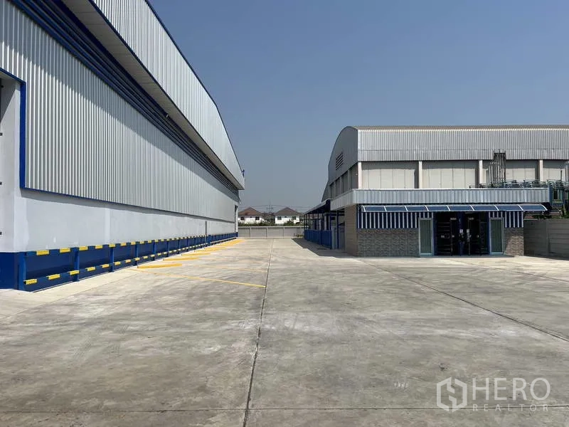 Warehouse for rent in Khlong Luang, Pathum Thani - Expansive concrete yard between warehouses for parking and truck maneuvering.