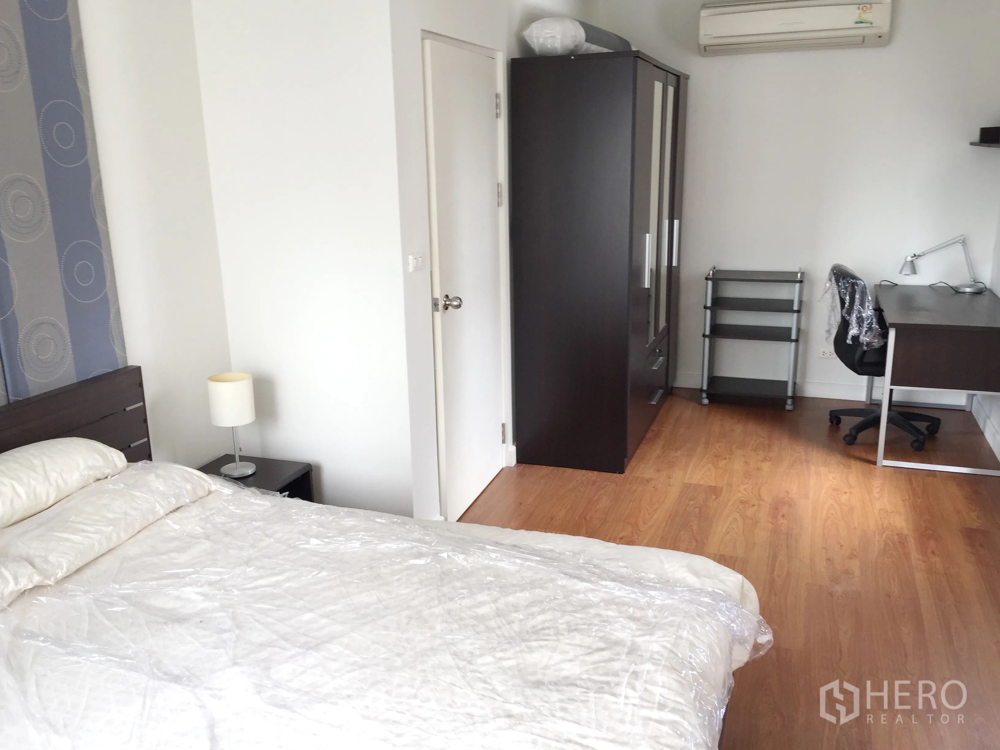 คอนโด ให้เช่าในKhlong Toei, Bangkok - มุมห้องนอนพร้อมตู้เสื้อผ้า โต๊ะทำงาน เก้าอี้ พื้นไม้ และเครื่องปรับอากาศ