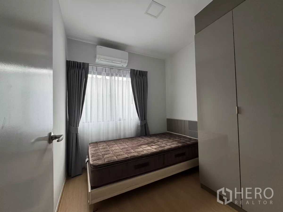 Townhouse for rent in Bang Phli, Samut Prakan - Cozy guest bedroom with bed, wardrobe and wall-mounted air conditioner.