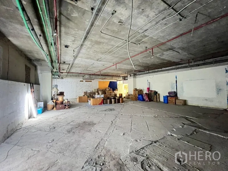 零售空间 出租 - 广角视角的大型混凝土零售空间，可见服务管线与存放箱。