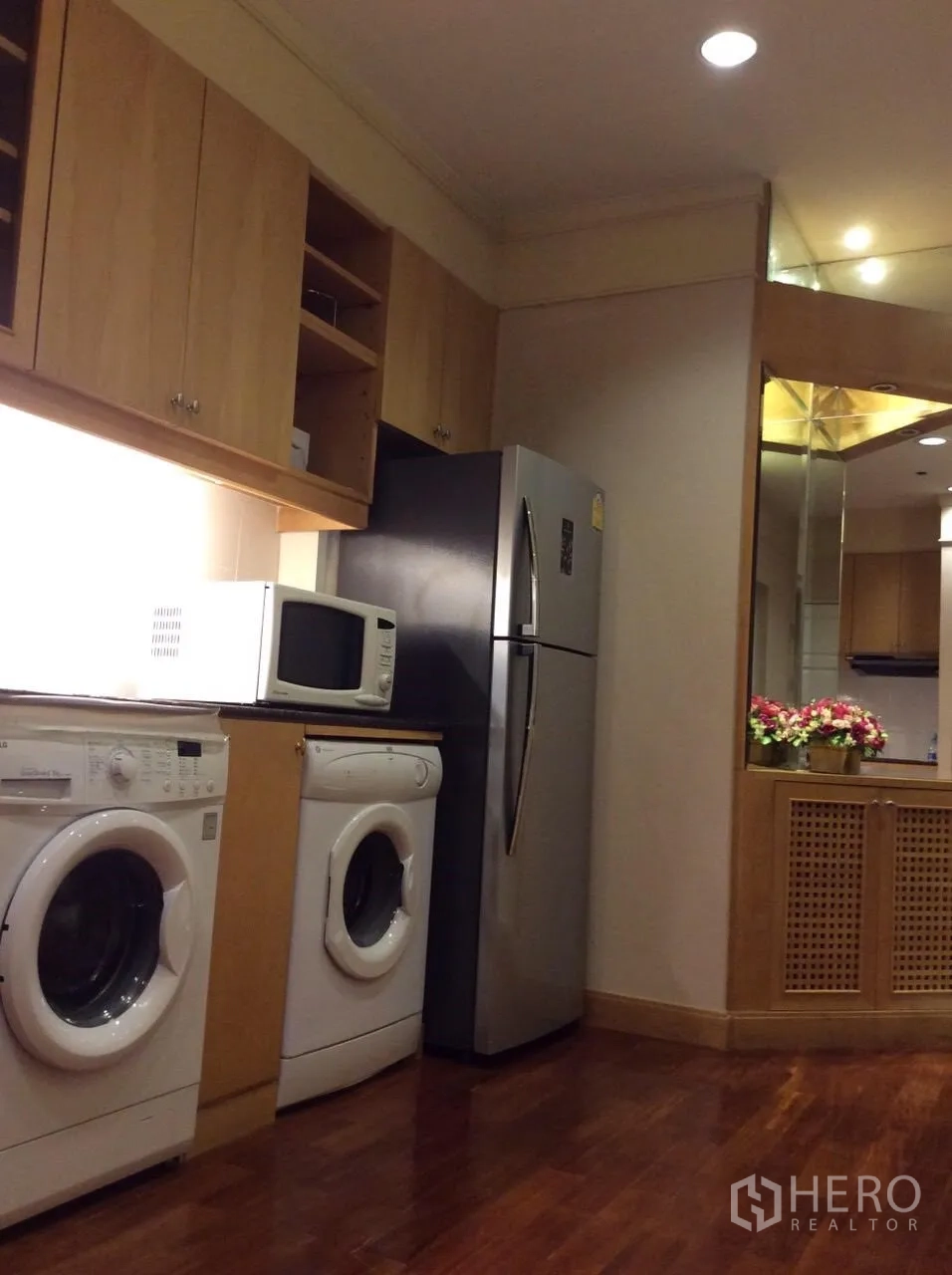 Condominium for rent in Pathum Wan, Bangkok - Compact kitchen with wood cabinetry, stainless refrigerator, microwave, and washer and dryer.