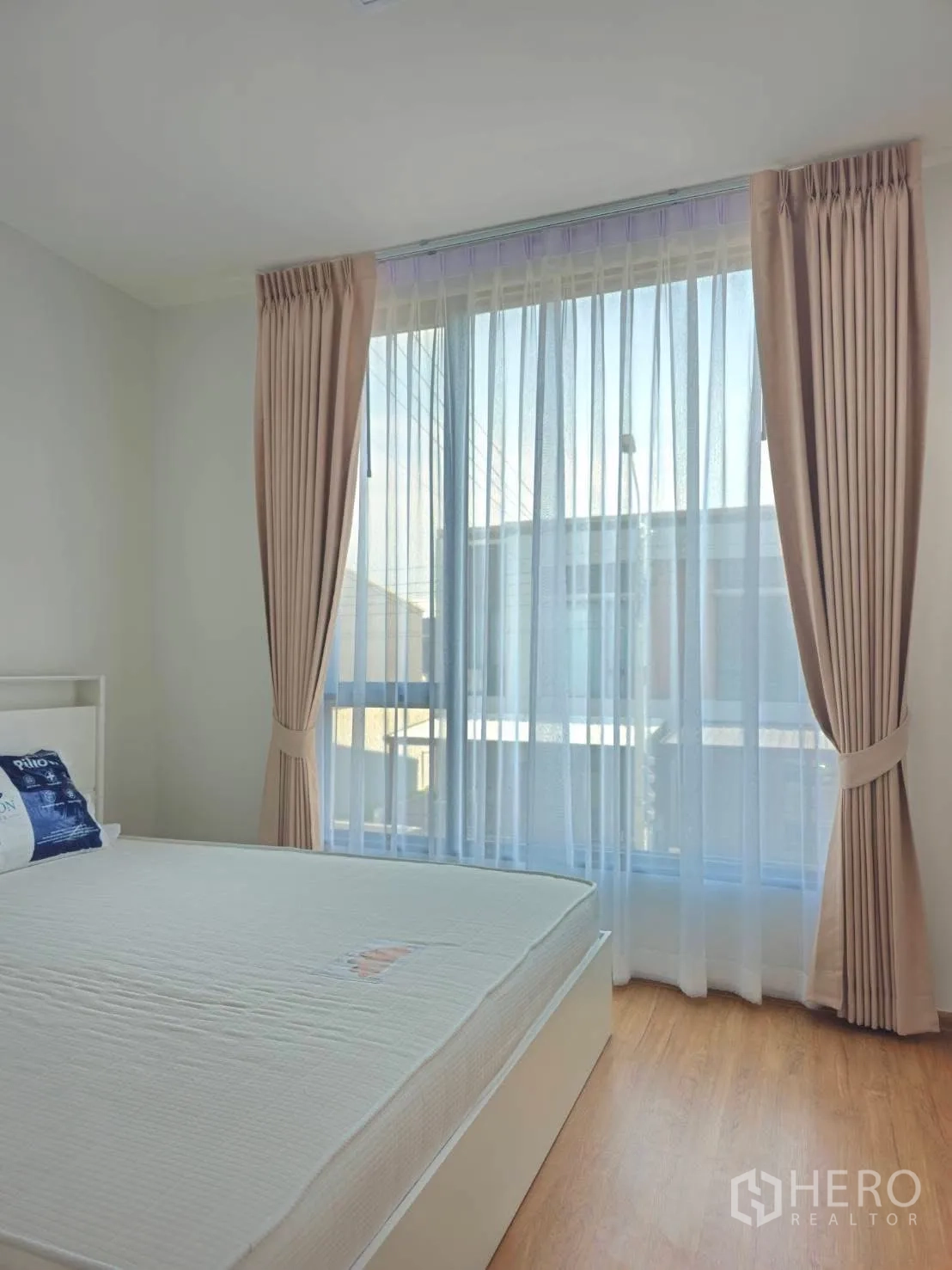 Townhouse for rent in Bang Phli, Samut Prakan - Bedroom with a large floor-to-ceiling window dressed with sheer curtains.