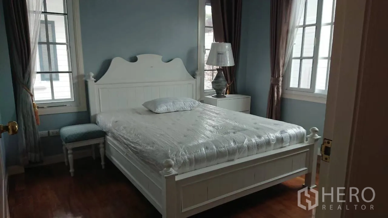 บ้าน ให้เช่าในMueang Samut Prakan, Samut Prakan - ห้องนอนอบอุ่น เตียงกรอบไม้สีขาว ผนังสีฟ้า และหน้าต่างใหญ่พร้อมผ้าม่าน