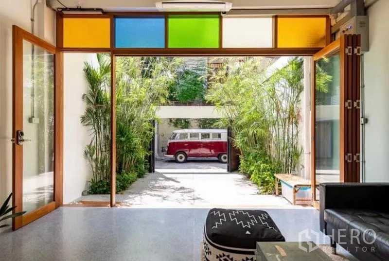 Townhouse for rent in Pathum Wan, Bangkok - Open-plan living area with folding glass doors to a bamboo-lined driveway.