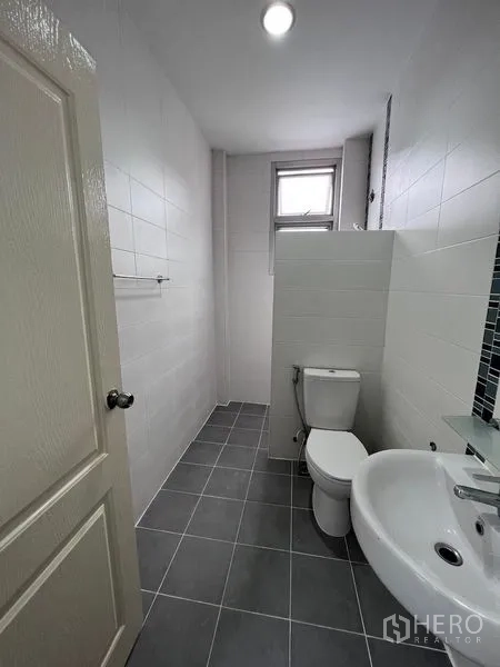 Home Office for sale in Lat Krabang, Bangkok - Long bathroom with gray floor tiles, partition wall and toilet at the rear.