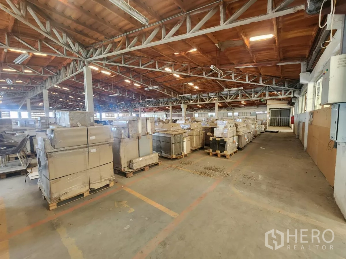 工厂 出租在Mueang Samut Sakhon, Samut Sakhon - 宽阔仓库地面，托盘成排，荧光灯照明。