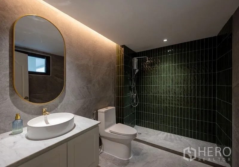 Condominium for sale in Watthana, Bangkok - Contemporary bathroom with a green tiled walk-in shower and backlit oval mirror.