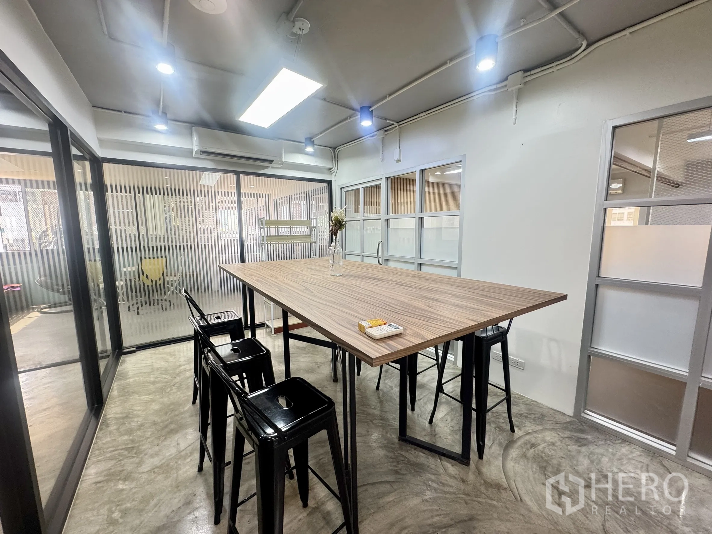 Office Space for rent in Bang Rak, Bangkok - Collaborative room with a high bar-style table, stools, and sliding glass doors.