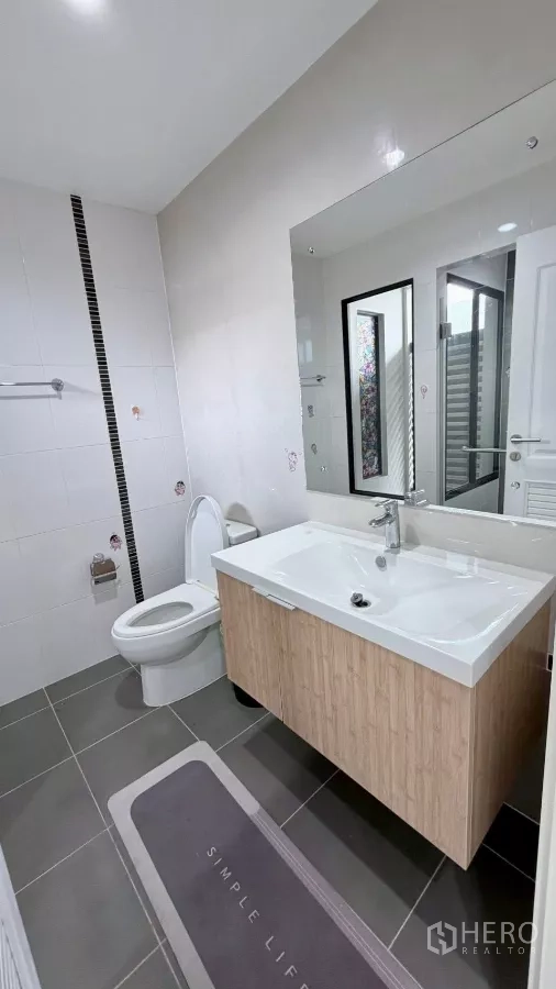 独立式住宅 出租或出售在Bang Phli, Samut Prakan - 整洁卫浴，带大镜面、洗手台与坐便器。