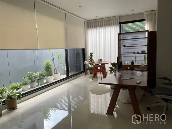 联排别墅 出售在Lat Phrao, Bangkok - 明亮的一层起居/工作区，落地窗与室内花园盆栽。