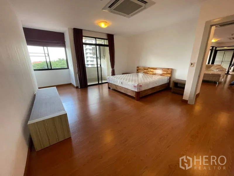 Condominium for rent in Watthana, Bangkok - Primary bedroom with balcony access, wood flooring, big windows and neutral decor.