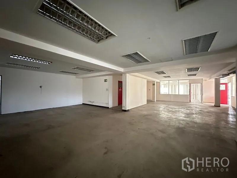 Warehouse for rent in Suan Luang, Bangkok - Open office floor showing red doors, windows and ample circulation space.
