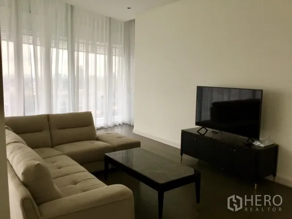 คอนโด ให้เช่าในPathum Wan, Bangkok - โซนรับแขกสไตล์โมเดิร์น มีโซฟา ตู้ทีวี และโต๊ะกลางหินอ่อน ขอบด้วยผ้าม่านโปร่ง.