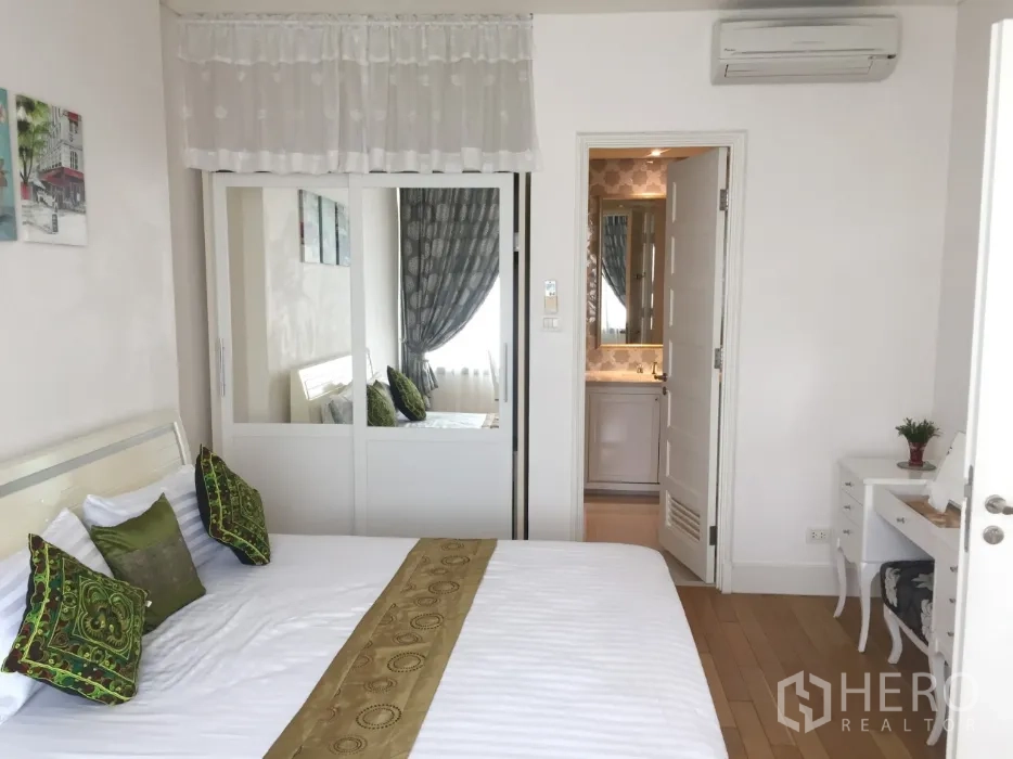 คอนโด ให้เช่าหรือขายในKhlong Toei, Bangkok - ห้องนอนโทนสบายตาพร้อมหมอนสีเขียว ตู้เสื้อผ้าบานกระจก และประตูเข้าสู่ห้องน้ำในตัว