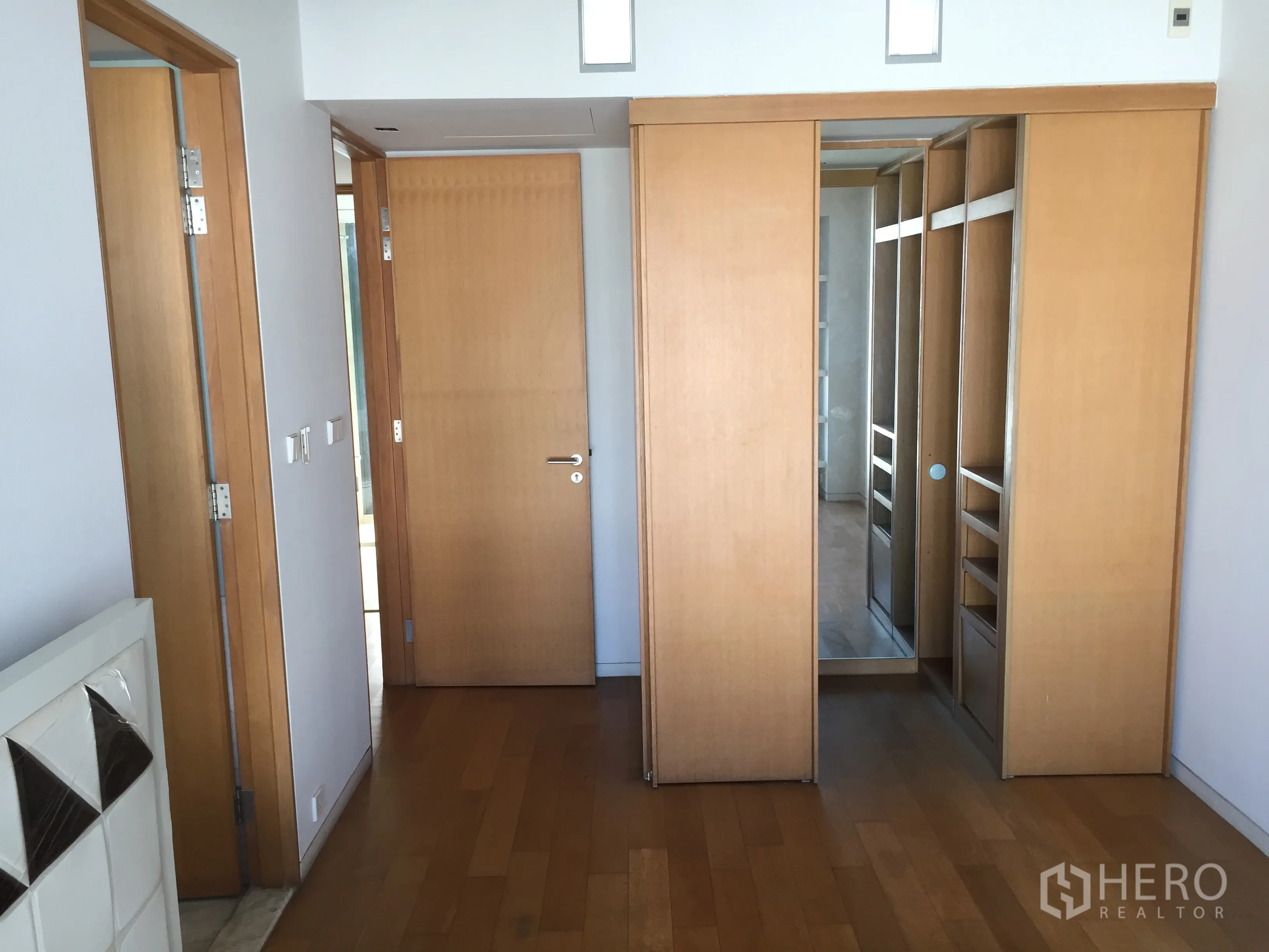 Condominium for sale in Sathon, Bangkok - Hallway with wooden floors leading to built‑in sliding wardrobes and mirrored closet.