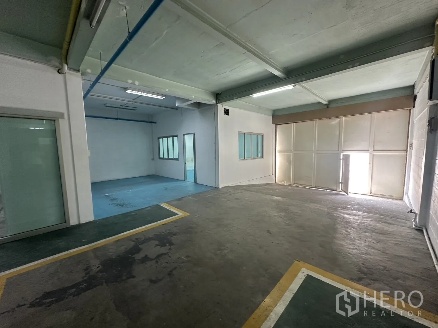 Warehouse for rent in Bang Na, Bangkok - Loading bay area with sliding doors, internal windows and blue epoxy floor room.