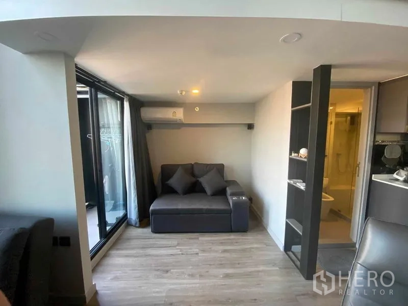 公寓 出租或出售在Sathon, Bangkok - 起居角落配沙发，推拉玻璃门通往阳台，旁见浴室入口。