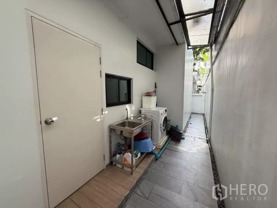 Detached House for rent or sale in Bueng Kum, Bangkok - Covered side-yard laundry area with washing machine, stainless sink and storage.