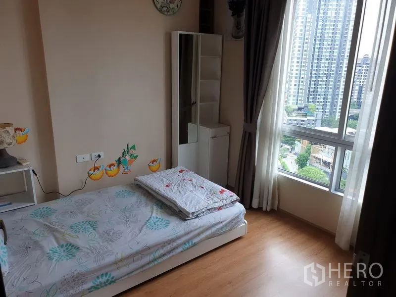 Condominium for rent in Watthana, Bangkok - Second bedroom with single bed, storage and large corner window.