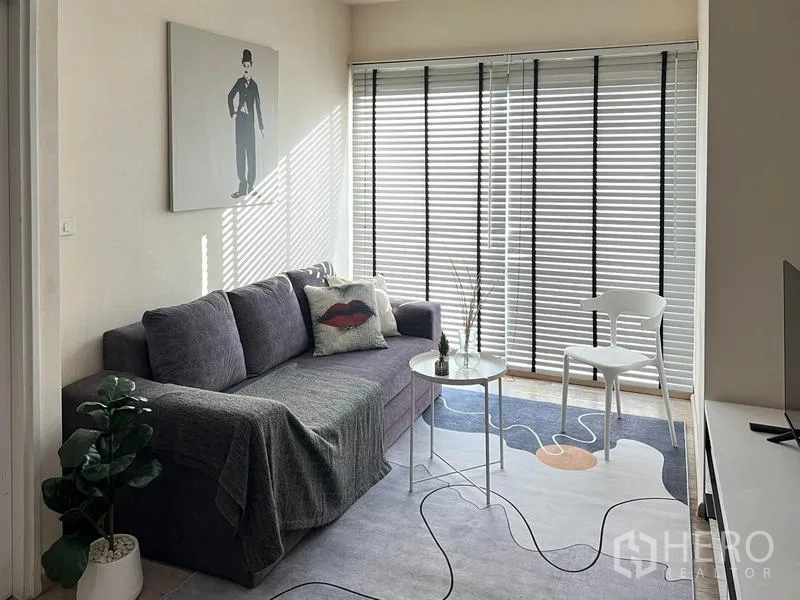 公寓 出租在Khlong Toei, Bangkok - 明亮客厅，灰色沙发、百叶窗和图案地毯上的小茶几