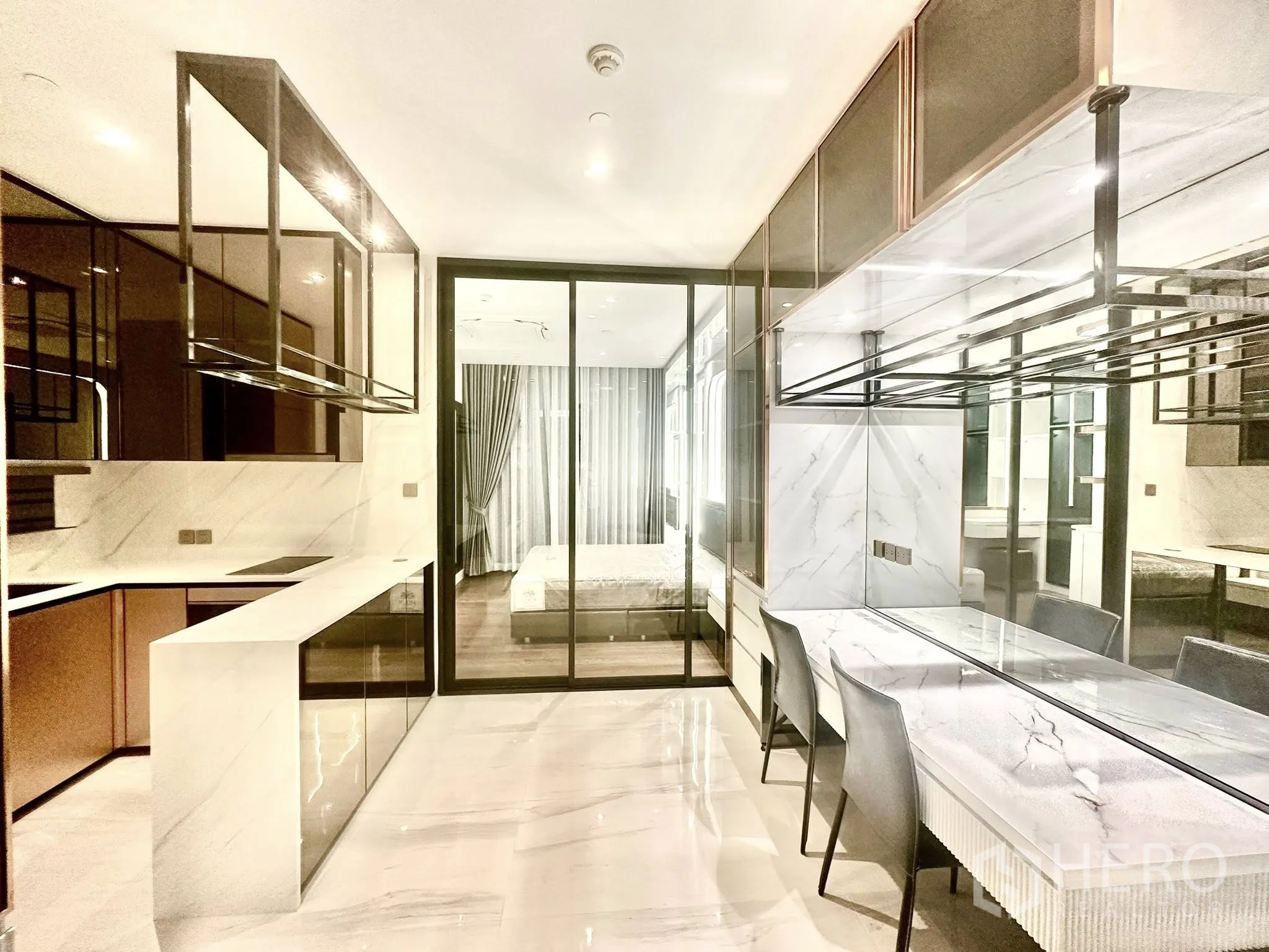 คอนโด for rent in Sathon, Bangkok - ครัวเปิดโทนหินอ่อนพร้อมเคาน์เตอร์ยาวติดกับบาร์ทานอาหารหันสู่ห้องนอน
