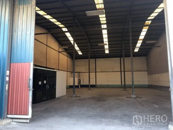 Warehouse for rent in Lat Krabang, Bangkok - Open warehouse interior with high ceiling, steel columns, skylight roof panels, and wide entry.