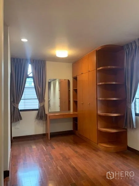 Detached House for rent in Ratchathewi, Bangkok - Bedroom with built-in wooden wardrobe, dressing table and hardwood flooring.
