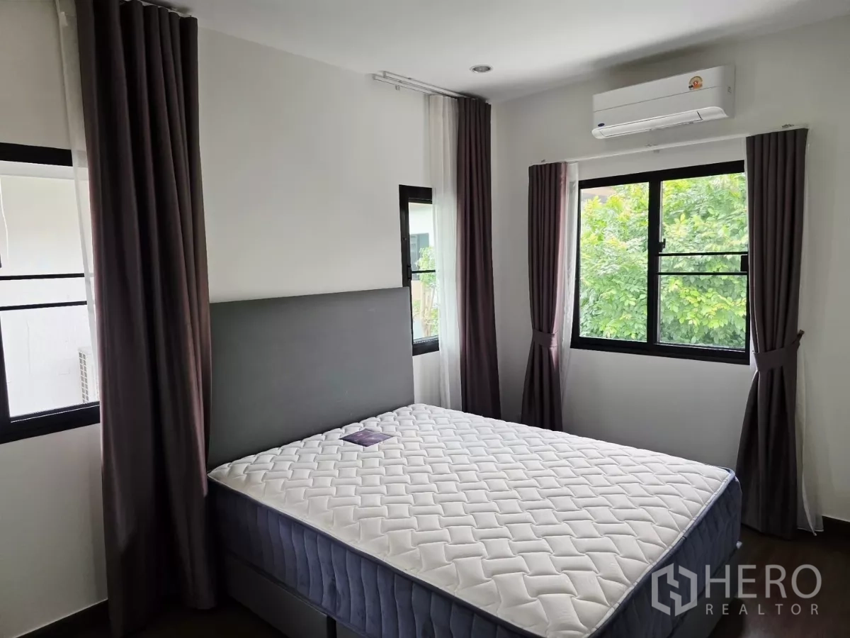 Detached House for rent in Prawet, Bangkok - Secondary bedroom with bed, two-sided windows, blackout curtains and air conditioner.