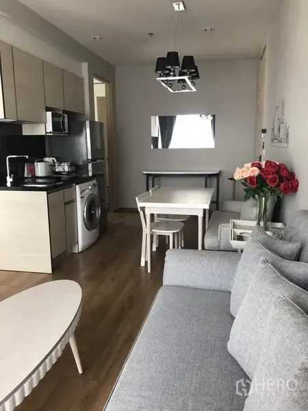 คอนโด ให้เช่าในKhlong Toei, Bangkok - ห้องนั่งเล่นและรับประทานอาหารแบบเปิด พร้อมครัวบิวท์อิน พื้นไม้ โซฟาสีเทา และเครื่องซักผ้าในห้อง คอนโดสุขุมวิท