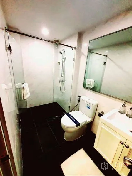 公寓 出售在Bang Rak, Bangkok - 现代卫浴，玻璃淋浴房、坐便器、大镜子与洗手台。