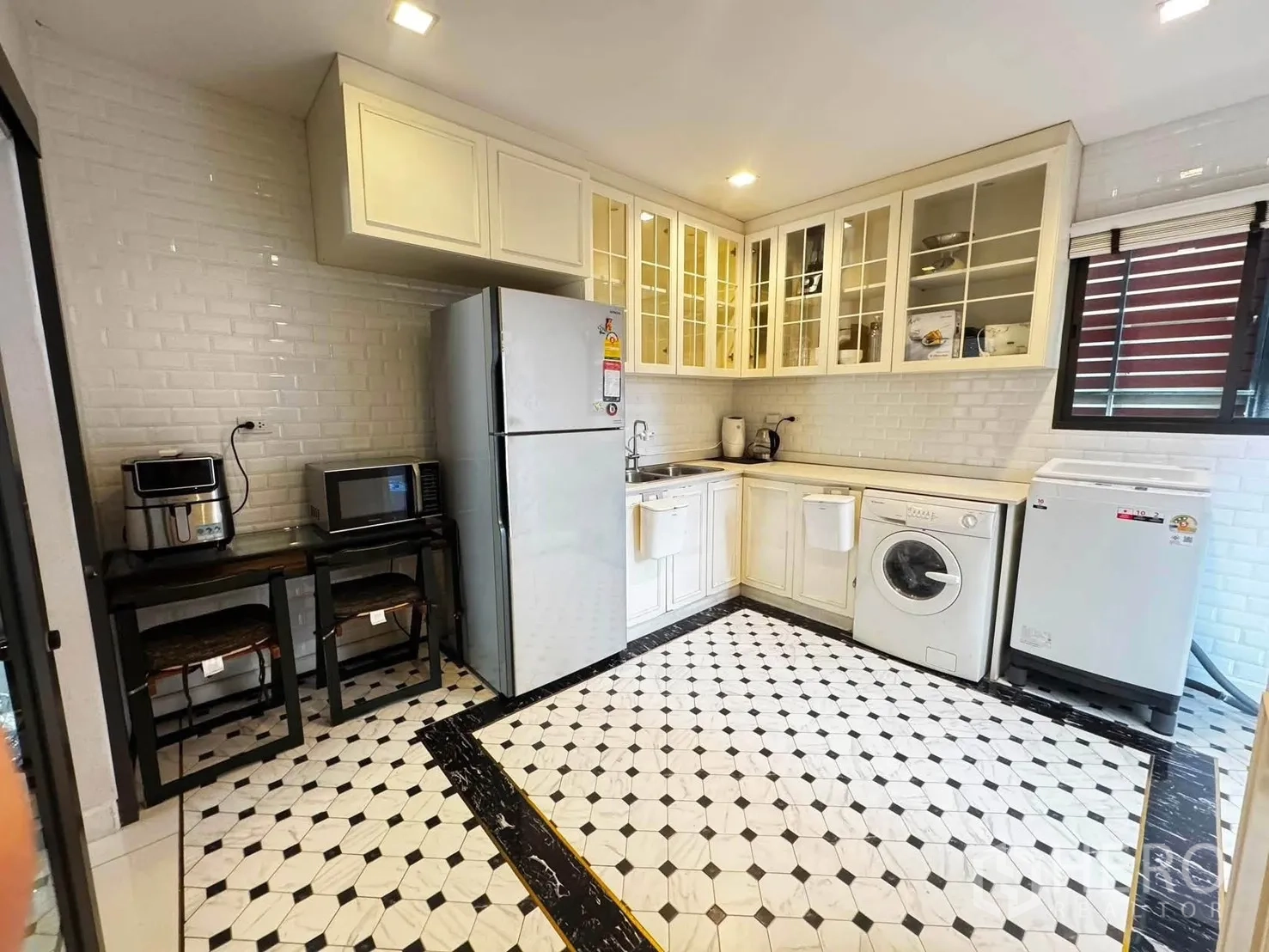 独栋房屋 for rent in Saphan Sung, Bangkok - 厨房配白色橱柜、砖纹墙面、几何花砖地面与家电。