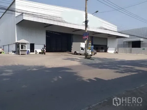 Warehouse for rent in Nonthaburi - Street‑front steel‑clad warehouse with wide covered loading bays, guard booth, and truck access.