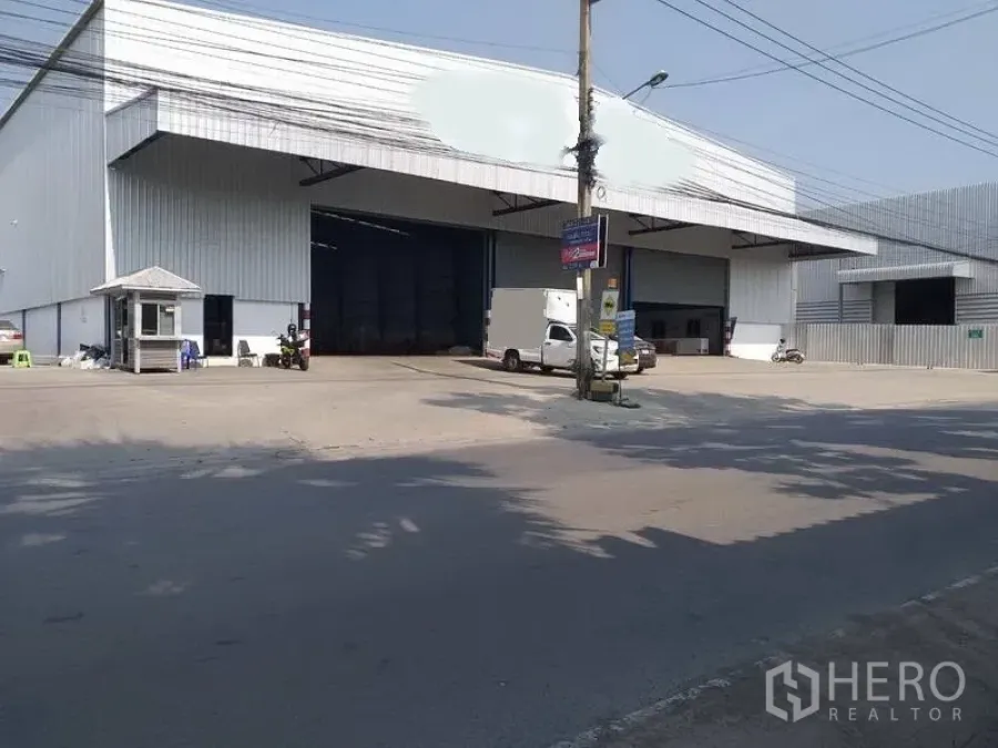 Warehouse for rent in Nonthaburi - Street‑front steel‑clad warehouse with wide covered loading bays, guard booth, and truck access.