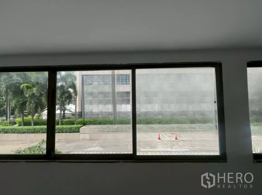 零售空间 出租在Pathum Wan, Bangkok - 大窗外景，可见棕榈树与建筑前的人行道