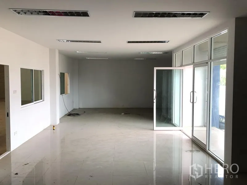 Factory for rent or sale in Bang Sao Thong, Samut Prakan - Ground-floor office area with glass frontage, tiled floors, and fluorescent lighting.