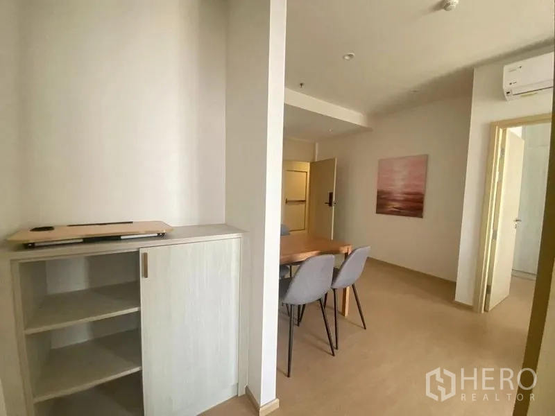 Condominium for rent in Watthana, Bangkok - Entry hall with built‑in storage cabinet leading to a dining area with modern chairs and minimal décor.