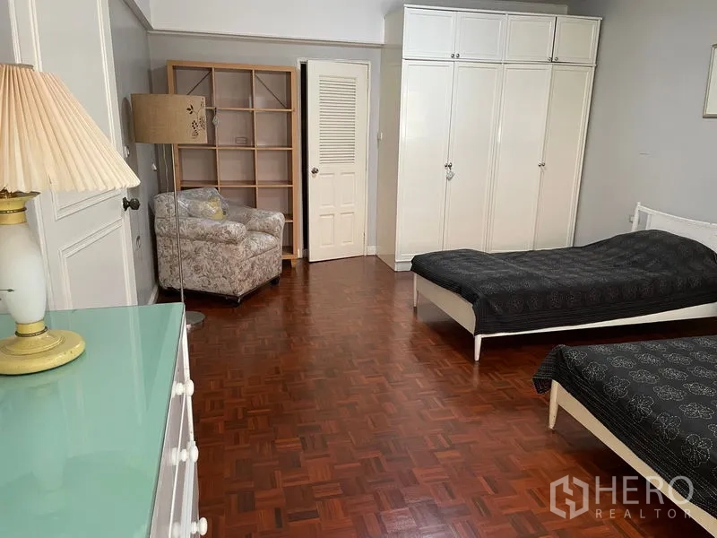 公寓 出租在Watthana, Bangkok - 宽敞卧室，拼花木地板，双床及白色嵌入式衣柜。