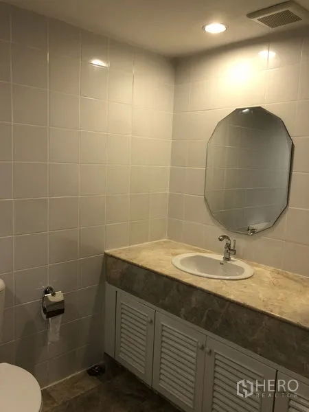 Condominium for rent or sale in Sathon, Bangkok - Bathroom vanity with stone countertop, oval mirror, sink and toilet.