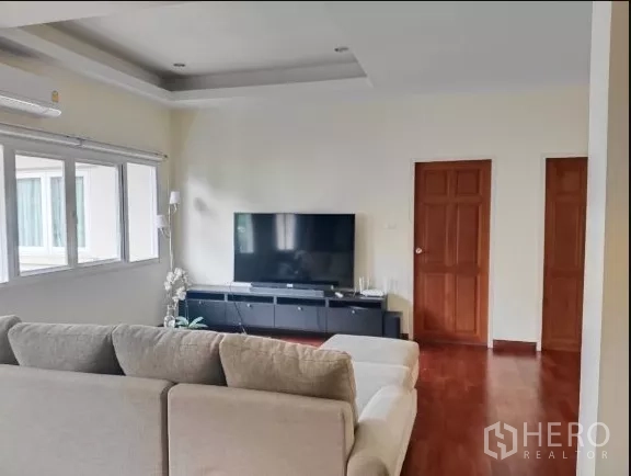Detached House for rent in Huai Khwang, Bangkok - Living area with sectional sofa facing a flat-screen TV